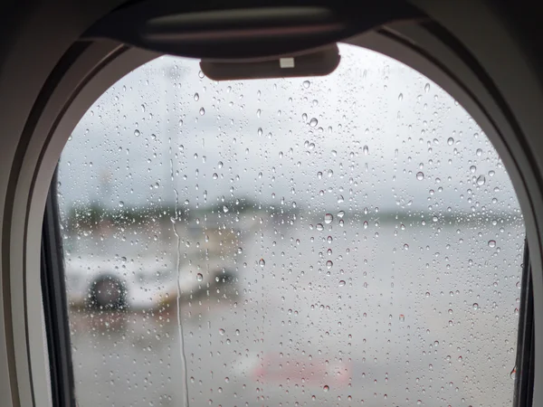 Gota de agua en la ventana del espejo del avión en el día lluvioso mientras aterriza en el aeropuerto. Seguridad en el transporte y concepto de viaje . — Foto de Stock