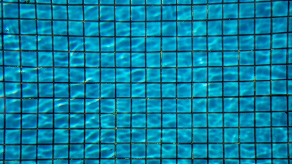 Eau bleue déchiré dans la piscine avec mosaïque de carreaux de céramique en arrière-plan — Photo