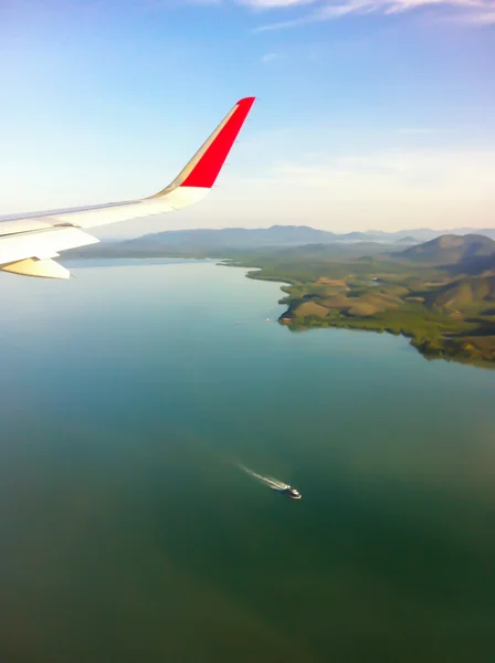 Defokussierung des Blicks aus dem Flugzeug, Flugzeugflügel mit blauem Himmel und Wolken über der Insel Phuket in Thailand, Boot im andamanischen Meer. — Stockfoto