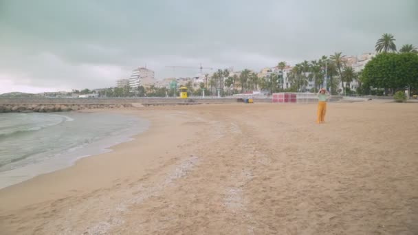 Giovane donna che cammina vicino alla spiaggia in tempo ventoso Filmato Stock