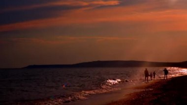 Sahilde yürüyen genç ailenin siluetleri