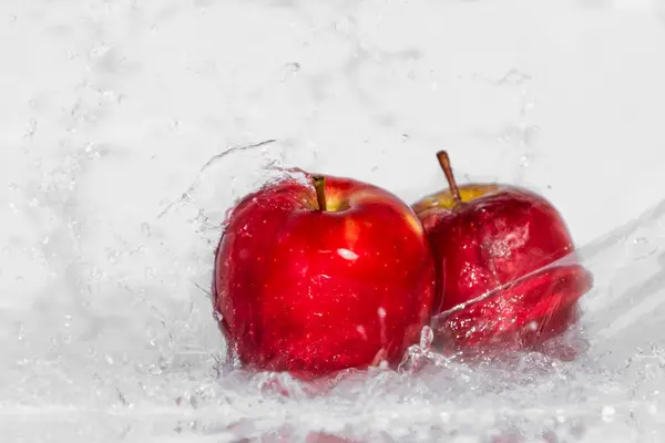 Roter Apfel im Spritzwasser Stockbild