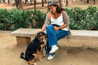 Şehir parkında bir bankta oturan kadın sadık köpeğini nazikçe okşuyor, sorumlu bir hayvan bakımı gösteriyor ve dışarıda sevgili hayvan arkadaşının arkadaşlığından keyif alıyor.