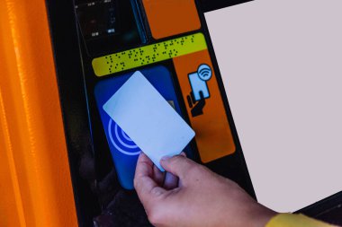 NFC sembollü toplu taşıma makinesindeki boş akıllı kartı tıklatan kişi, modern teknolojiyle seyahat etmek için hızlı, ulaşımsız ve kullanışlı bir ödeme yapıyor