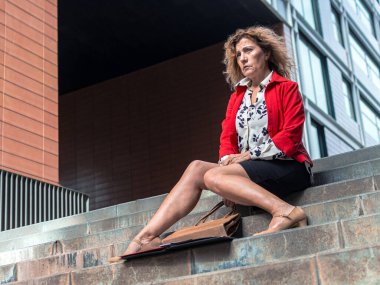 Kasaba merdivenlerinde tek başına oturan üzgün bir iş kadını, istihdam sorunları yaşıyor, finansal kriz yaşıyor ve zor bir dönemdeki belirsiz geleceği hakkında stres yaşıyor.