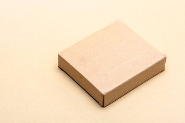 Kapalı kahverengi karton kutu sade bir arka planda izole edilmiş, ambalaj, nakliye, teslimat, minimalist tasarım ve eko dostu tüketici ürünlerini temsil ederek, kopya için yer sağlıyor
