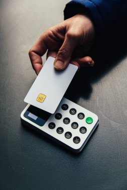 Karanlık bir yüzeydeki modern ödeme terminaline boş bir emv çipi eklemek, güvenli finansal işlemleri ve nakitsiz ticareti temsil ediyor.