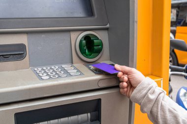 Açık hava ATM 'sinden para çeken, kart yuvasına çip kartı takan ve güvenli bir banka işlemi için tuş takımına şifre takan biri.