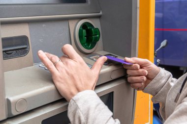 Açık hava para makinesinde bankacılık işlemi yapan kişilerin elleri, yuvaya kredi veya banka kartı takmak ve para çekmek veya diğer finansal hizmetler için bir pim girmek
