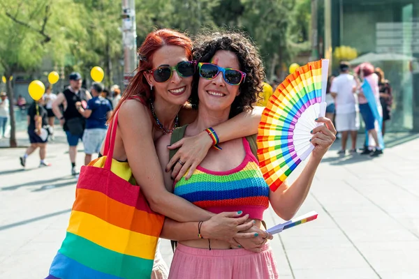 Gökkuşağı aksesuarları giyip kucaklaşan, atmosferin tadını çıkaran, çeşitliliği, kapsamı ve aşkı coşkulu bir lgbtq artı gurur etkinliğinde kutlayan iki kadın.