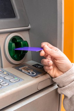 Otomatik veznedar makinesine canlı bir mor banka kartı yerleştirmek, bankacılık, para çekme ya da denge soruşturması için finansal işlem yapmak.