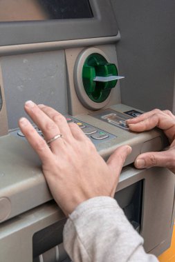 Bir kadının elleri ATM 'ye bağlanıyor, deliğe bir banka kartı sokuyor ve bir kimlik numarası giriyor - şifre - tuş takımına, finansal işlemleri tamamlıyor.