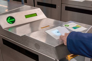 Metalik bir metro turnikesi okuyucusundaki beyaz, bağlantısız, akıllı bir kart yeşil bir ok ve toplu taşıma ulaşımı için aydınlatılmış ödeme alanını gösteriyor.