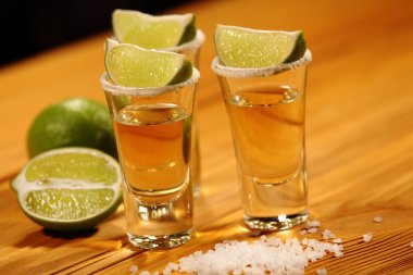 Üç kısa bir dilim limon ve tuz yanında alkol ile eski rustik masa vintage doku ile bardaklar