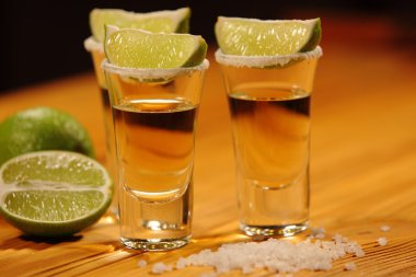 Üç kısa bir dilim limon ve tuz yanında alkol ile eski rustik masa vintage doku ile bardaklar