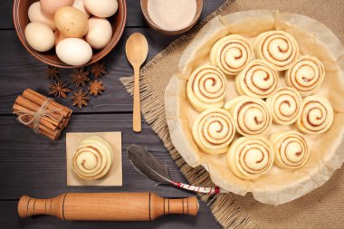 Yumurta ve mutfak araçları bir arka plan siyah kurulların rustik tablosunun yanındaki kavurma için hazırlanmış çiğ tarçın rulo