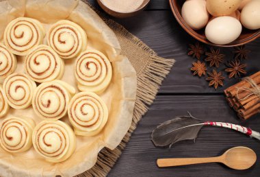 Yumurta ve mutfak araçları bir arka plan siyah kurulların rustik tablosunun yanındaki kavurma için hazırlanmış çiğ tarçın rulo