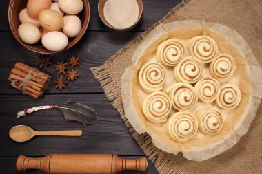 Yumurta ve mutfak araçları bir arka plan siyah kurulların rustik tablosunun yanındaki kavurma için hazırlanmış çiğ tarçın rulo