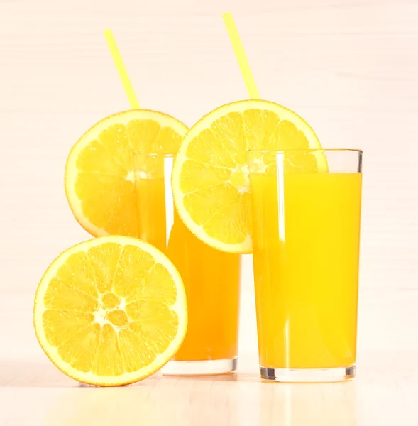 Limun oranye segar atau jus dalam gelas di sebelah seluruh buah dan irisan oranye pada latar belakang abu-abu terang — Stok Foto