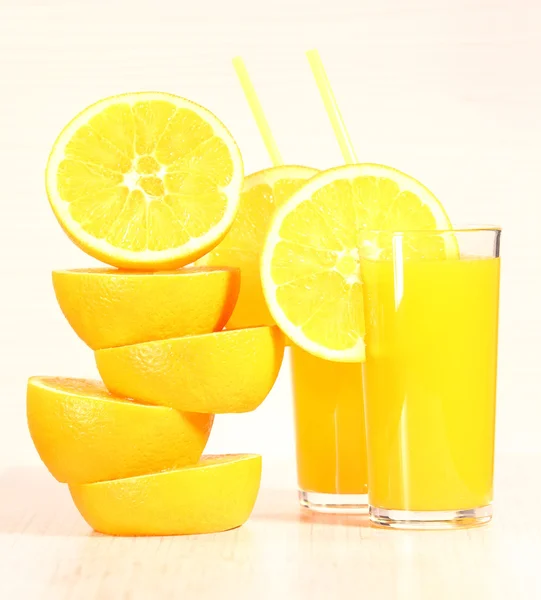 Fresh orange lemonade or juice in a glass next to the whole fruit and orange slices on a light gray background — Stock Photo, Image