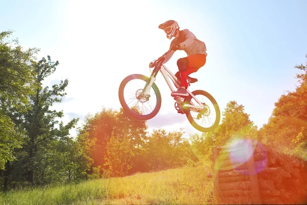 Sportler in Sportbekleidung auf einem Mountainbike-Sprung auf dem Sprungbrett — Stockfoto