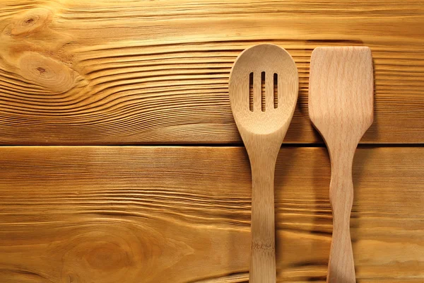 The composition of wooden spoon and kitchen spatula lying  on a panel of vintage brown boards with free space for text advertising of food or restaurant menu design. — Stock Photo, Image