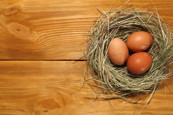 La composizione di uova di pollo che giacciono in un nido d'erba su un pannello di tavole marroni vintage con spazio libero per la pubblicità testuale di cibo o design del menu del ristorante . — Foto Stock