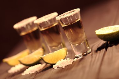 Vintage doku ile eski bir rustik tabloda üç kısa bardak alkol yanında bir dilim limon ve tuz ile vardır. Seçici odak