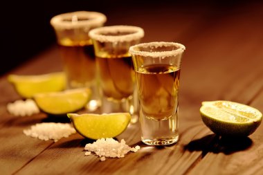 Vintage doku ile eski bir rustik tabloda üç kısa bardak alkol yanında bir dilim limon ve tuz ile vardır. Seçici odak