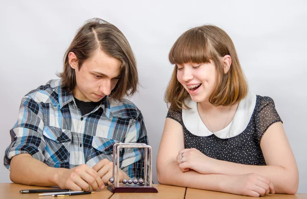 Adolescentes à mesa assistindo as bolas modelo lei de conservação do impulso — Fotografia de Stock