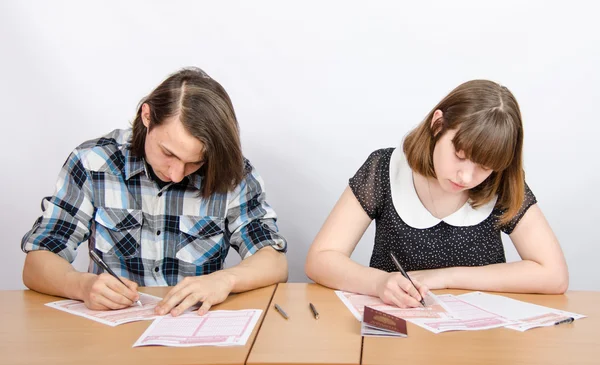 Подростки за столом, заполненным бланками экзаменов — стоковое фото