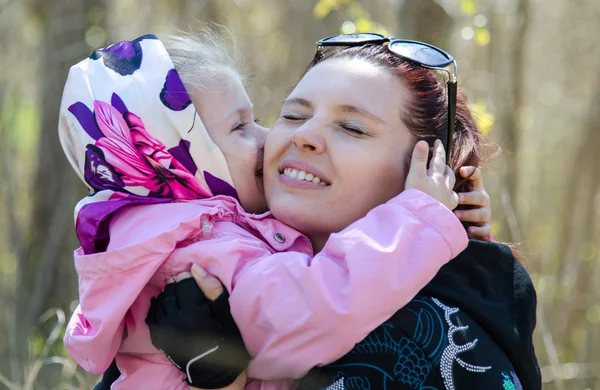 Mãe feliz abraçando sua menina em um lenço na natureza — Fotografia de Stock