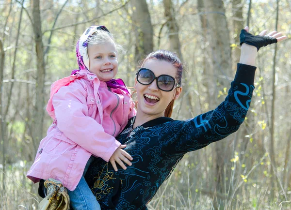 Mãe feliz em óculos de sol segura uma menina em um lenço na natureza — Fotografia de Stock