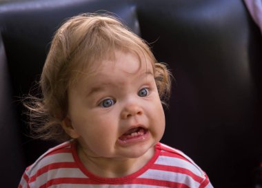 Küçük kız dişlerini göstererek yüzünü buruşturuyor.