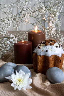 Paskalya. Bej bir waffle havlusunda, fındıklı Paskalya pastası ve güzel gri renkli Paskalya yumurtaları var, ve tüm kompozisyon beyaz çiçekler ve yanan iki mumla süslenmiş..
