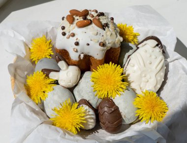 Paskalya. Sepette fındıklı bir pasta ve güzel gri renkli Paskalya yumurtaları, çikolatalı Paskalya yumurtaları ve tüm kompozisyon sarı karahindibalar ile süslenmiş..