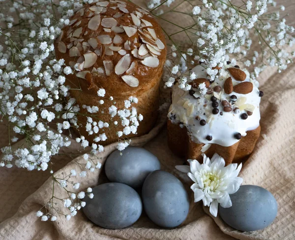 Paskalya. Bej bir waffle havlusunun üzerinde fındıklı bir pasta ve güzel gri renkte Paskalya yumurtaları var ve tüm kompozisyon beyaz çiçeklerle süslenmiş..