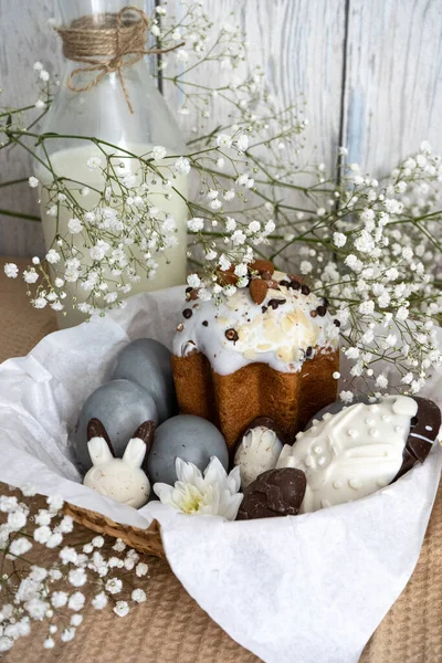 Paskalya. Sepette fındıklı bir pasta ve güzel gri renkli Paskalya yumurtaları var. Paskalya yumurtaları ve tüm kompozisyon beyaz çiçeklerle süslenmiş..