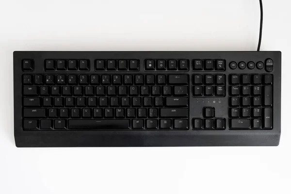 Siyah klavye beyaz masada. Yukarıdan görüntüle.