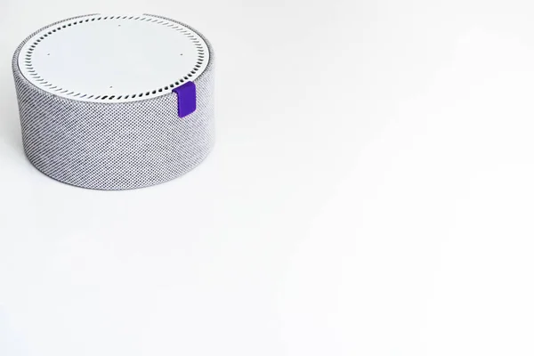 Gri ve beyaz tonlarda küçük, yuvarlak bir sütun beyaz bir masada duruyor..