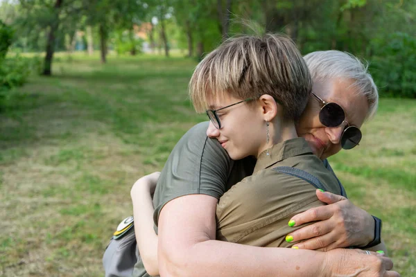Yaşlı, modaya uygun, modern, yaratıcı bir büyükanne ve şık ergen torunu bir yaz parkında yürüyor, gülümsüyor ve sarılıyorlar..
