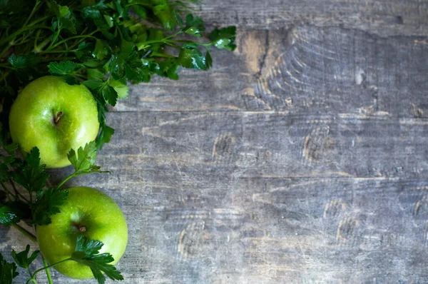 İki yeşil elma maydanozun yanında yatıyor..