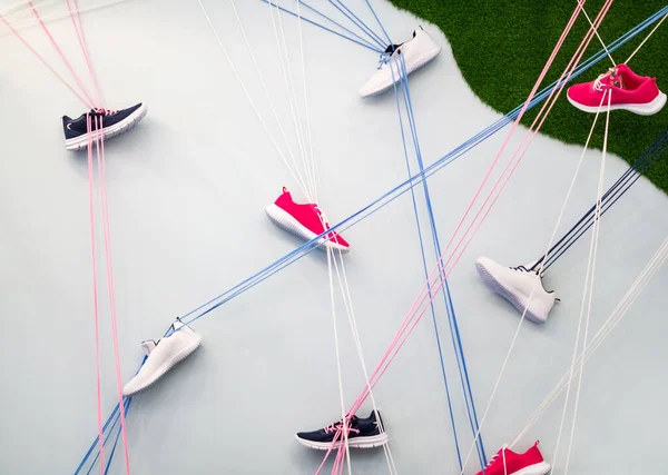 Sanat kurulumu. Beyaz arka planda, spor ayakkabıları pembe, beyaz ve mavi bağcıklar üzerine tutunur..