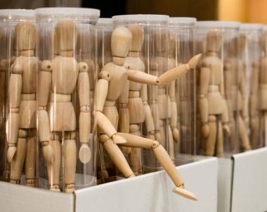 Şeffaf kutularda bir sürü tahta adam figürü var. Bir adam kaçmaya çalışıyor gibi görünüyor..