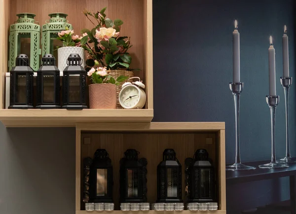 Mumları, şamdanları ve saksısı olan iki ahşap raf..