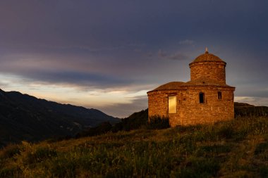 Küçük bir dağlık kilise, bir tapınak, bir ibadet evi, bir cami, gün batımına karşı bir taş bina ve şaşırtıcı derecede güzel bir gökyüzü..