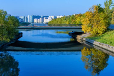 Duderhof Kanalı 'nın üzerindeki köprüde güneşli bir sonbahar gününde suya yansıyan modern çok katlı binalar var..