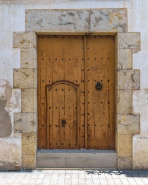 Tossa de Mar, Costa Brava, Katalonya, İspanya 'da tarihi duvarlı Vila Vella' da (eski kasaba) taş duvarlı konut duvarındaki aşınmış ahşap kapı.