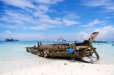 Öğlen eski ahşap bir tekne sahilde sallanıyor.