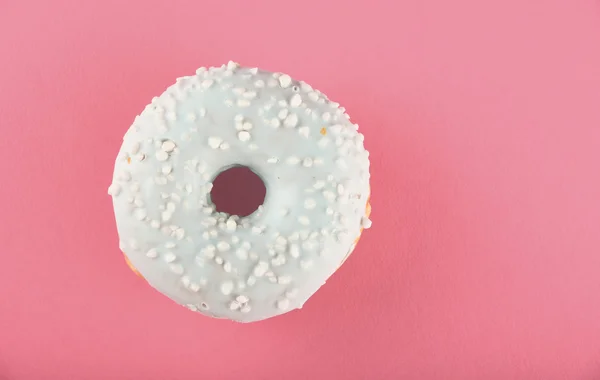 Donut con esmalte azul espolvorea sobre papel rosa —  Fotos de Stock